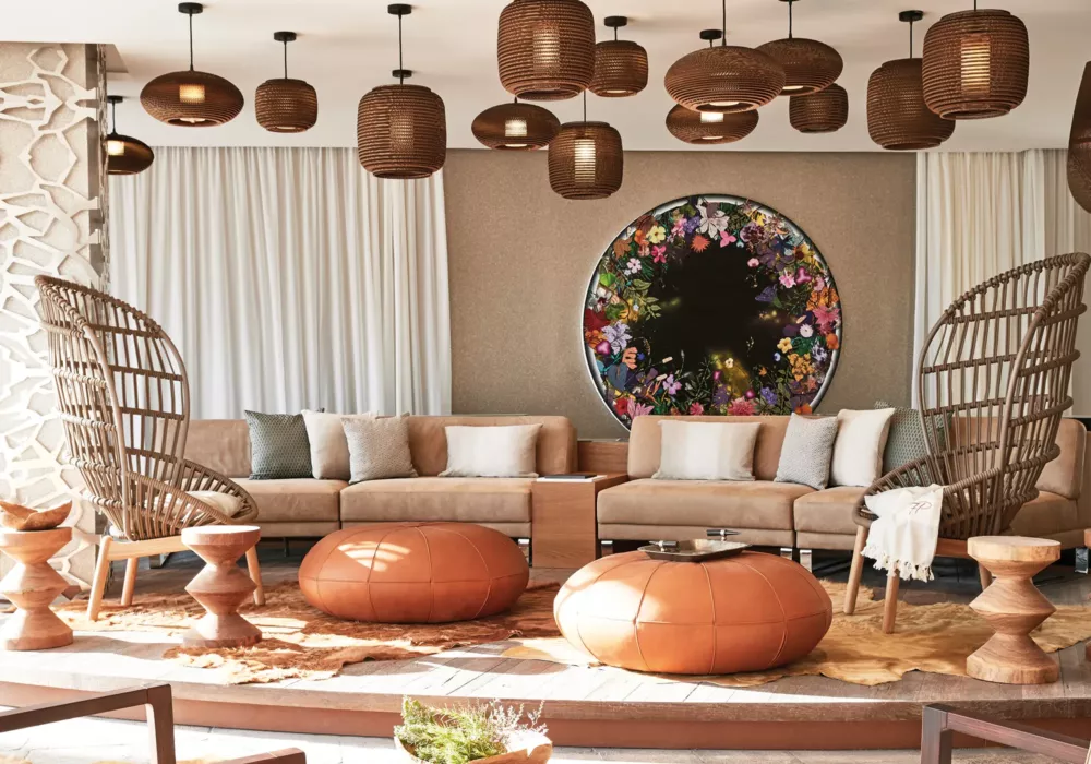 Luxuriöse Lounge mit modernen Rattanmöbeln, Lederhockern und einer stilvollen Wanddekoration mit floralen Elementen im 7Pines Resort Ibiza
