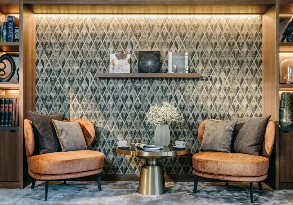 Elegante Leseecke im Grand Tirolia Kitzbühel mit gemütlichen Sesseln, stilvoller Wandgestaltung und dekorativen Regalen