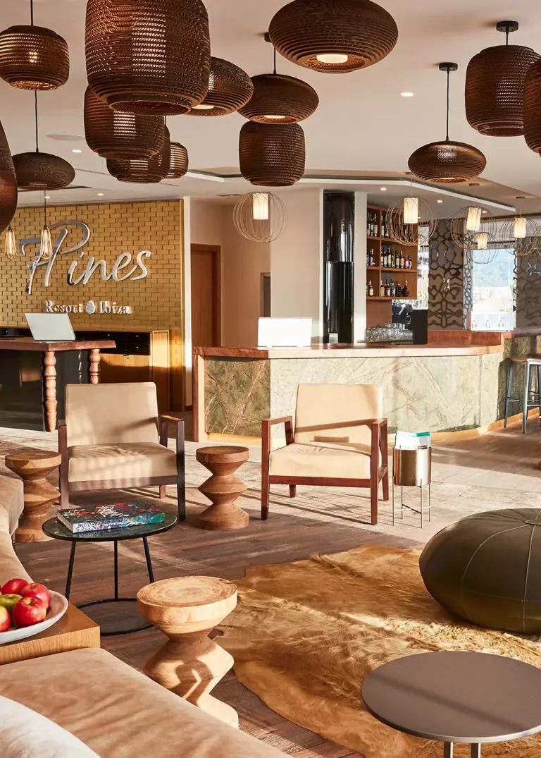 Elegante Lobby im 7Pines Resort Ibiza mit stilvollen Sitzmöbeln, warmen Holzelementen und einer luxuriösen Bar