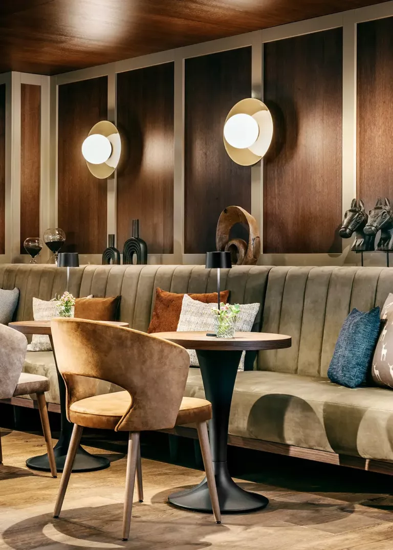 Stilvolle Lounge im Grand Tirolia Kitzbühel mit eleganter Sitzbank, warmen Holzakzenten und gemütlicher Beleuchtung