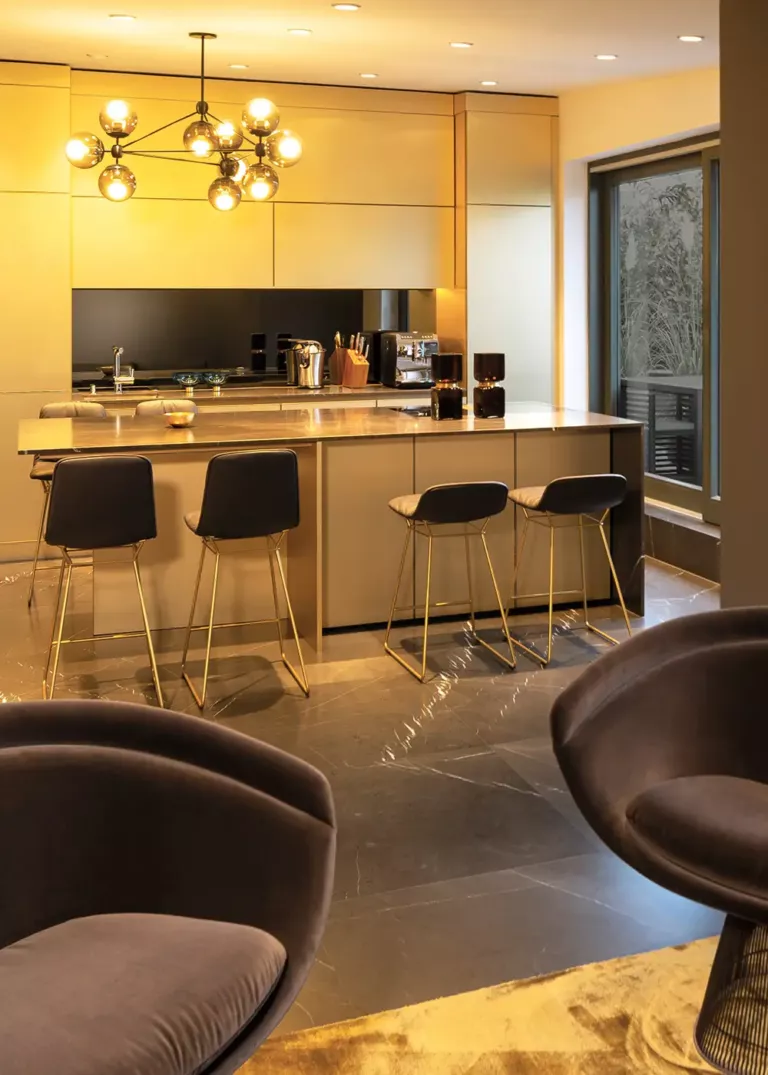 Exklusive Design-Küche im Private Penthouse Berlin mit goldenen Fronten, eleganter Kücheninsel und modernen Barhockern