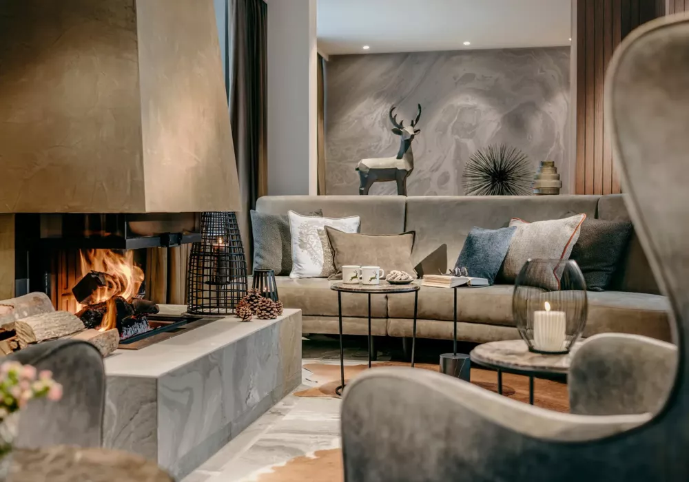 Gemütliche Kaminlounge im Grand Tirolia Kitzbühel mit stilvoller Einrichtung, warmem Feuer und eleganter Dekoration