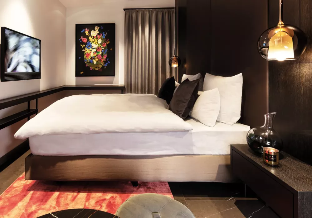 Luxuriöses Schlafzimmer im Private Penthouse Berlin mit Designer-Beleuchtung, dunklen Akzenten und moderner Kunst an der Wand