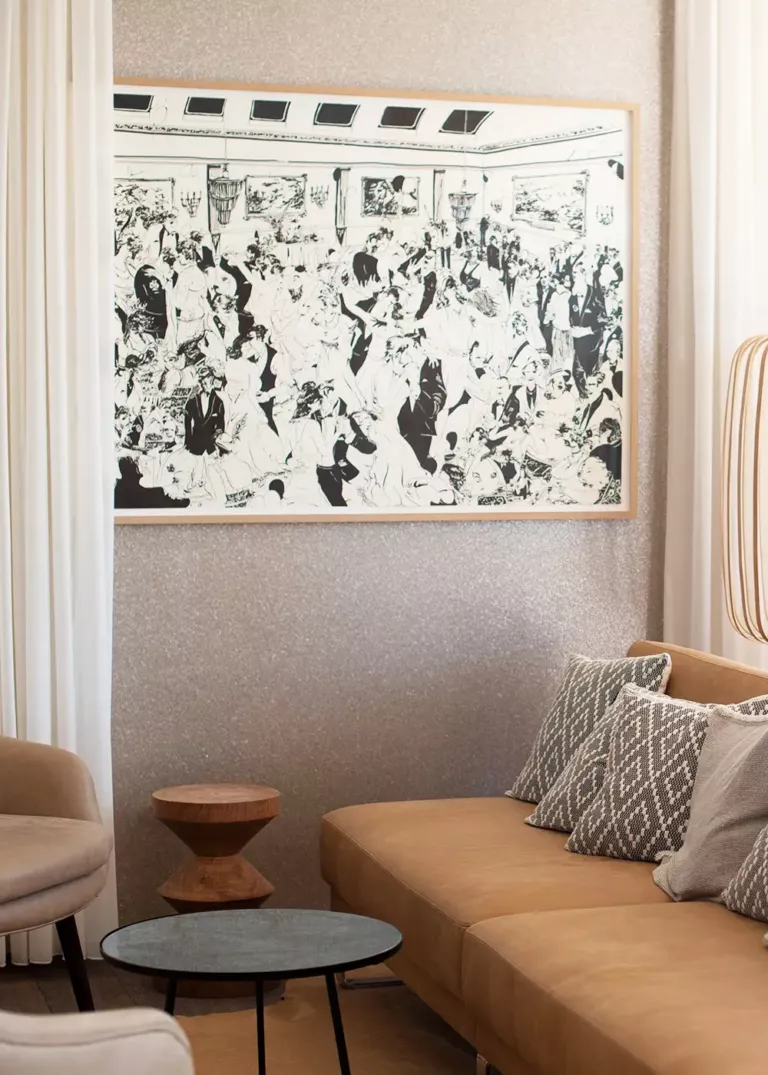 Gemütliche Sitzecke im 7Pines Resort Ibiza mit stilvollem Sofa, dekorativen Kissen und einem großen schwarz-weißen Kunstwerk an der Wand
