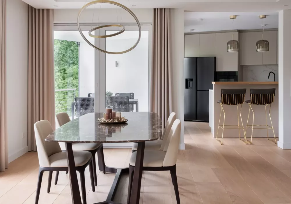 Hochwertiger Ess- und Küchenbereich in einer Privatwohnung in Köln mit Marmortisch, Designleuchten und moderner Küchentheke mit Barhockern