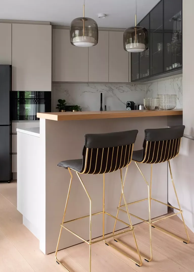 Exklusive Küche in einer Privatwohnung in Köln mit eleganter Küchentheke, goldenen Barhockern und hochwertigen Designleuchten